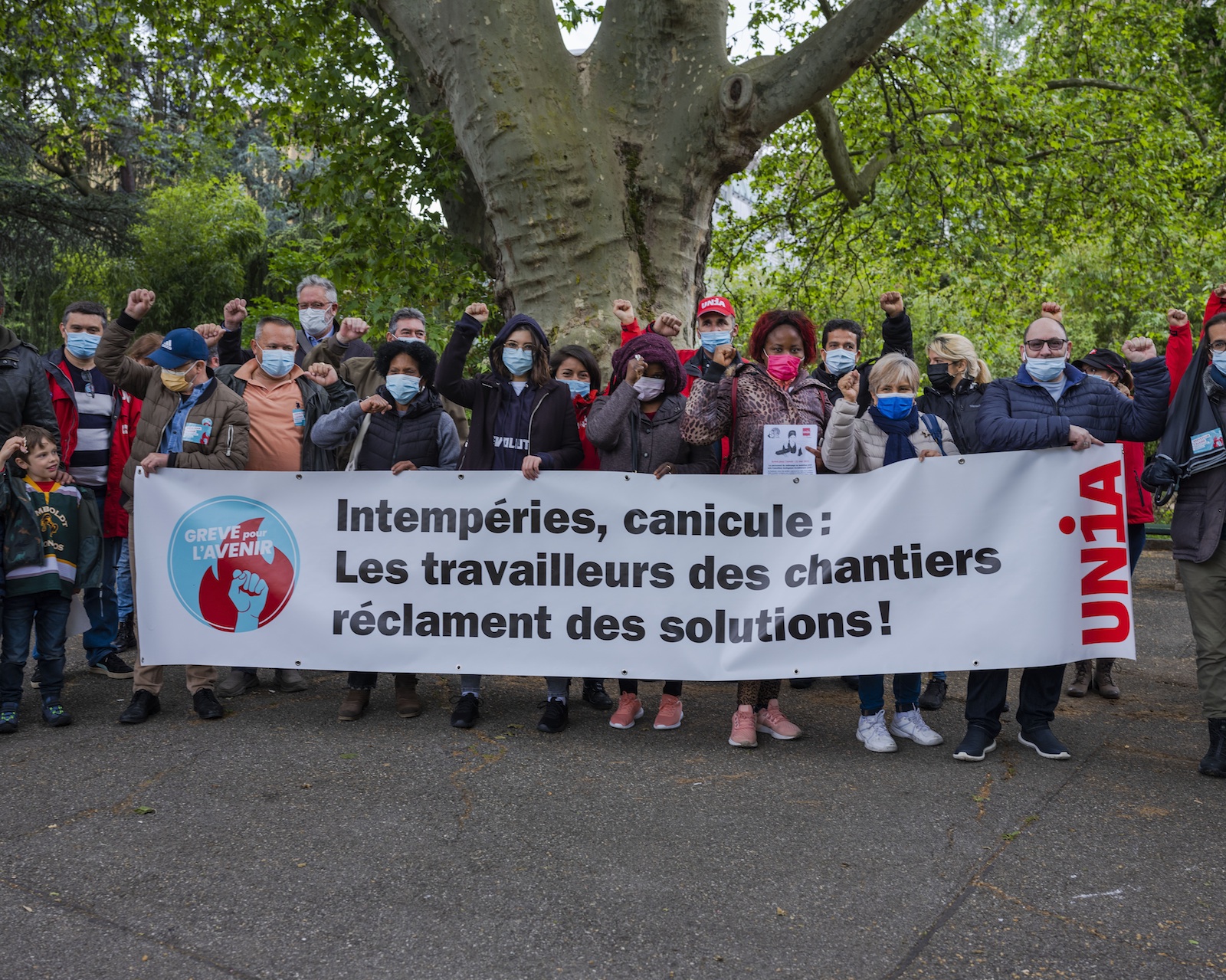 Secrétaires syndicaux et militants rassemblés derrière une banderole "Intempéries, canicule: les travailleurs des chantiers réclament des solutions."