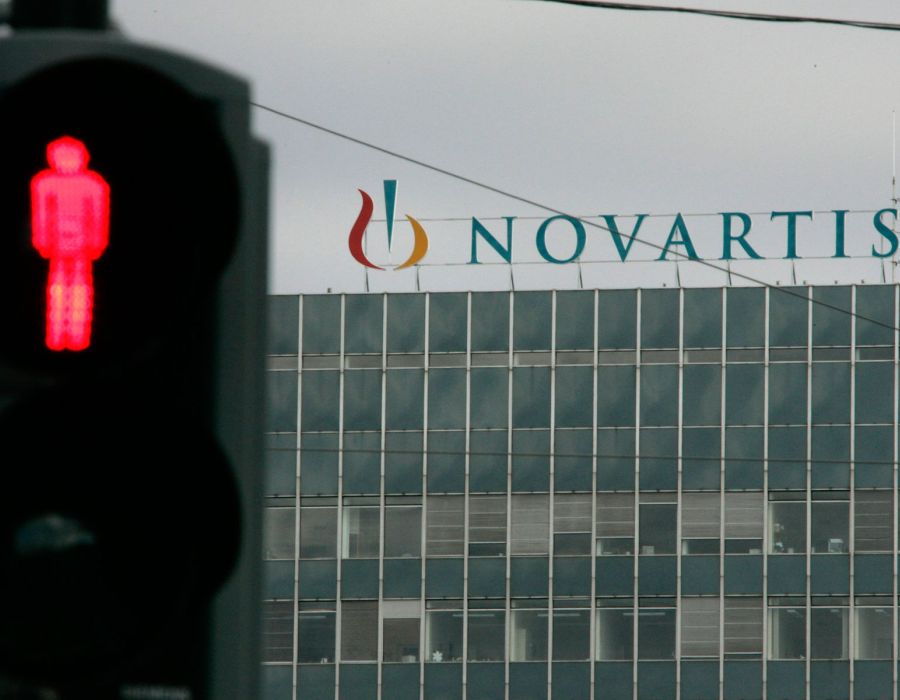 Bâtiment Novartis en arrière plan. Un feu rouge au premier plan.