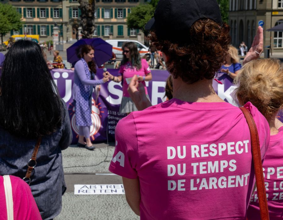 Lancement de la grève du 14 juin à Berne. De dos une femme portant un t-shirt "Du respect, du temps, de l'argent".