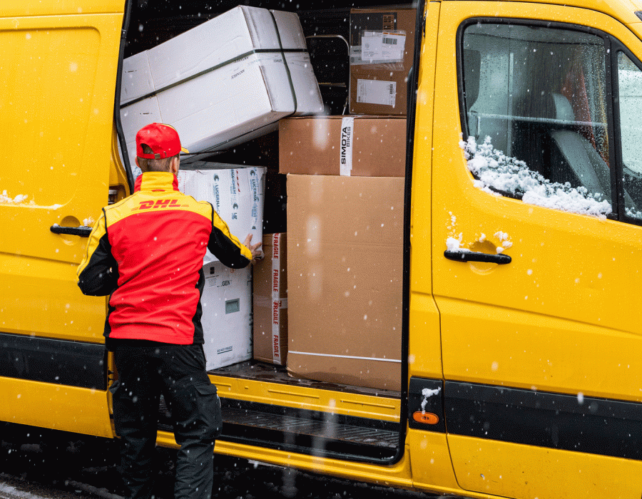 un employé DHL devant un camion plein de paquets