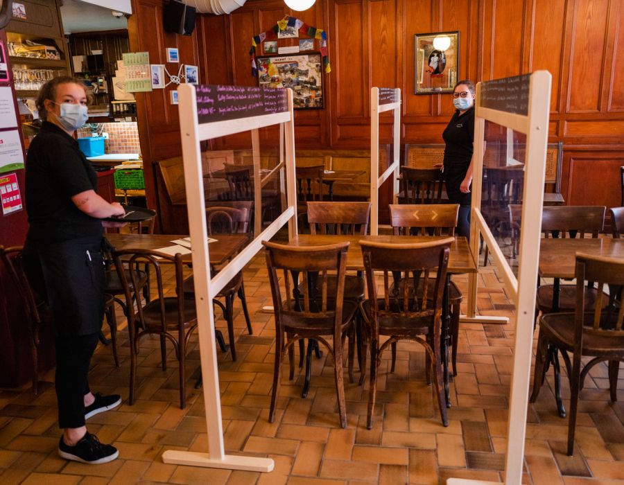 Intérieur du café du Grütli à Lausanne. Des plexiglas montés sur des cadres en bois séparent les tables et les employées portent le masque.