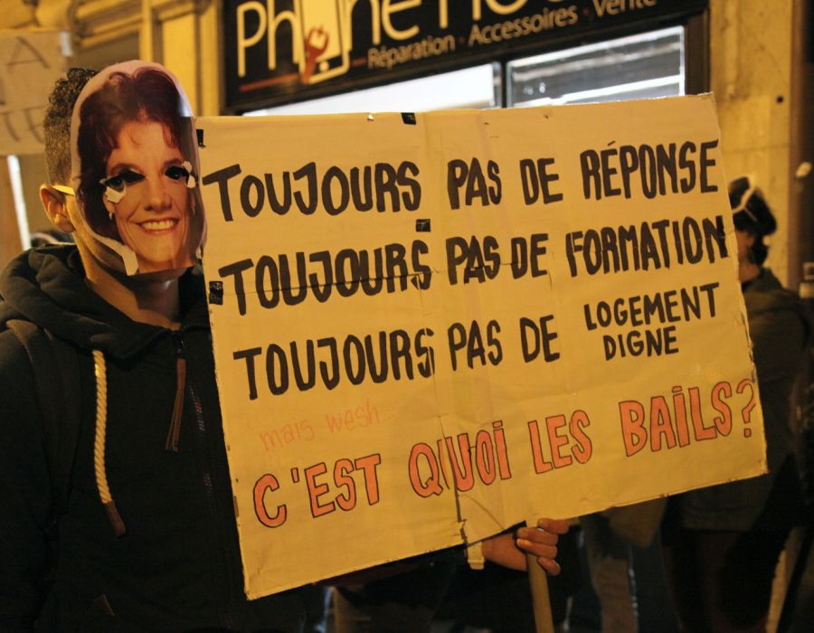 Un jeune manifestant masqué porte une pancarte sur laquelle on peut lire: toujours pas de réponse, toujours pas de formation, toujours pas de logement digne.