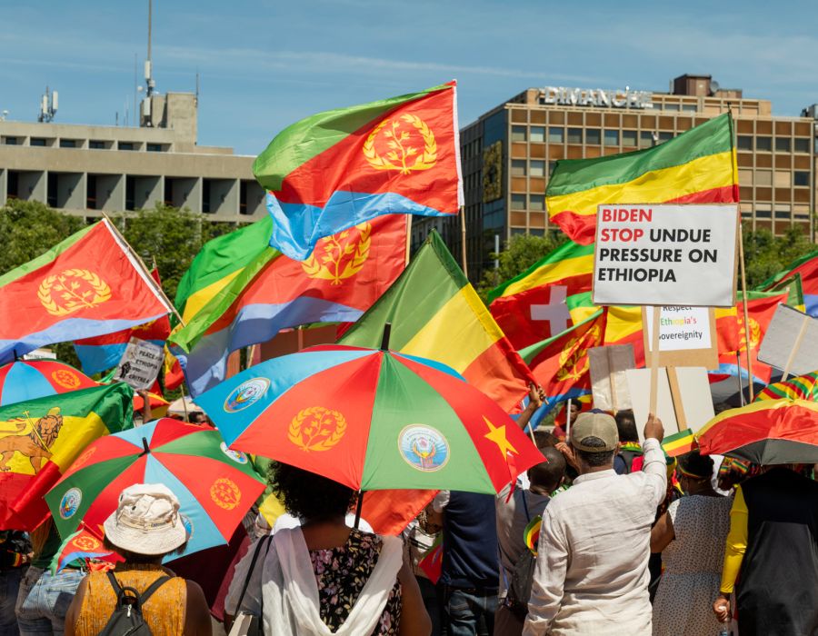 Manifestation avec drapeaux et parapluies multicolores.