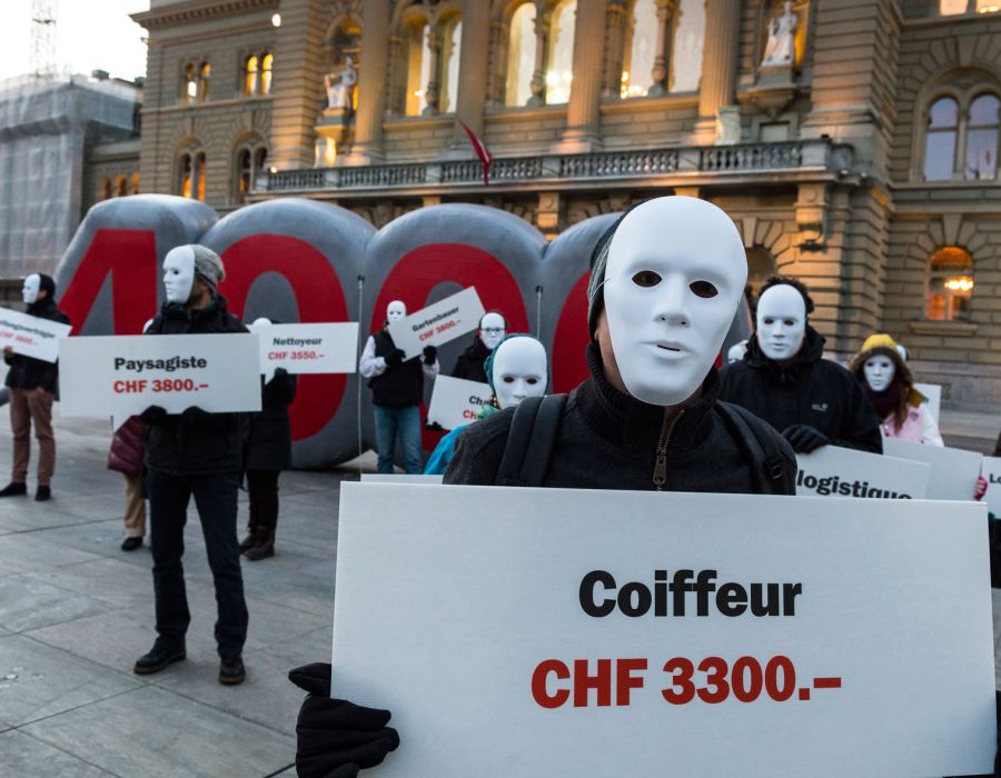 Militant maqué avec une pancarte "Coiffeur CHF 3300 francs".