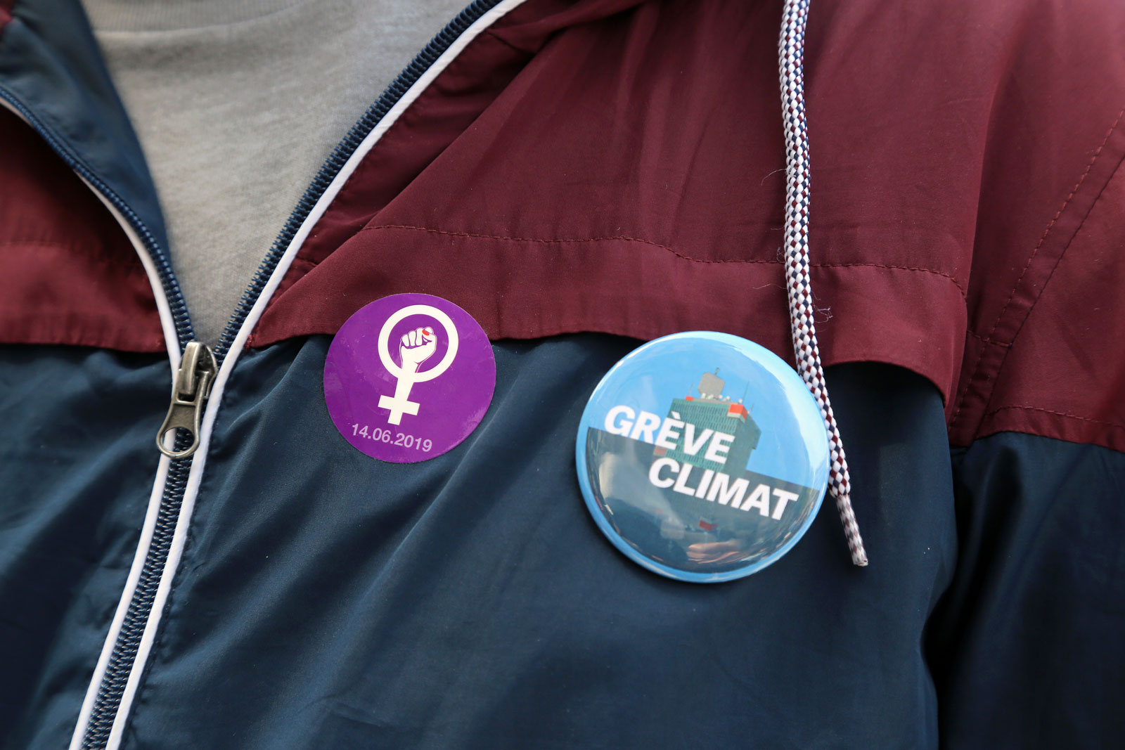 Une personne arbore le badge de la grève des femmes et celui de la grève pour le climat.