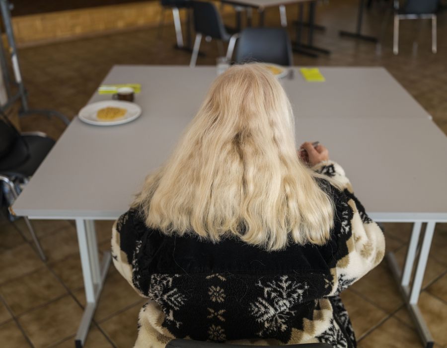 Femme assise à une table d'une aide alimentaire.