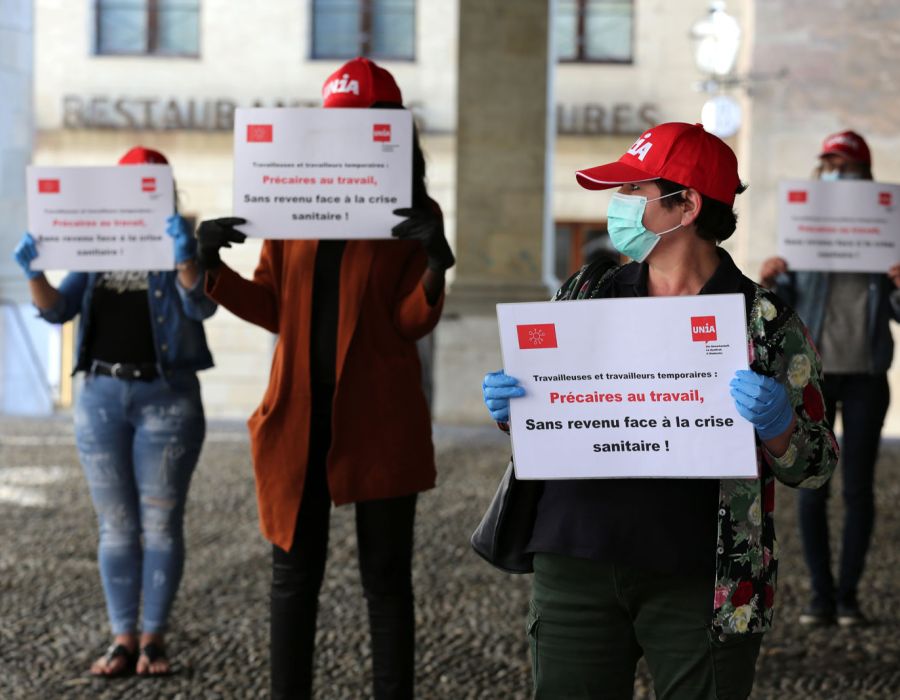 Action à Genève où des travailleurs temporaires vétus de masques chirugicaux et casquettes Unia affichent leurs revendications.