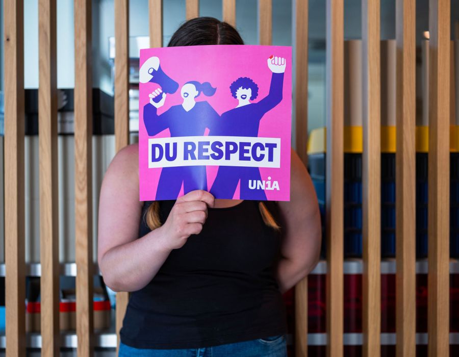 La travailleuse derrière une pancarte Unia "Du respect".