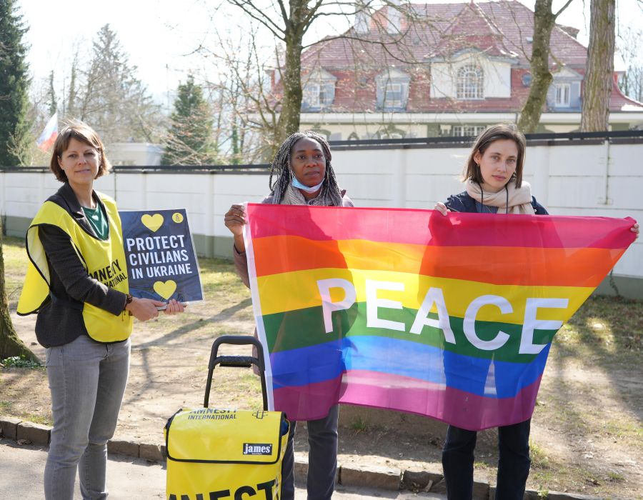 Personnes avec un drapeau devant l'ambassade de Russie.