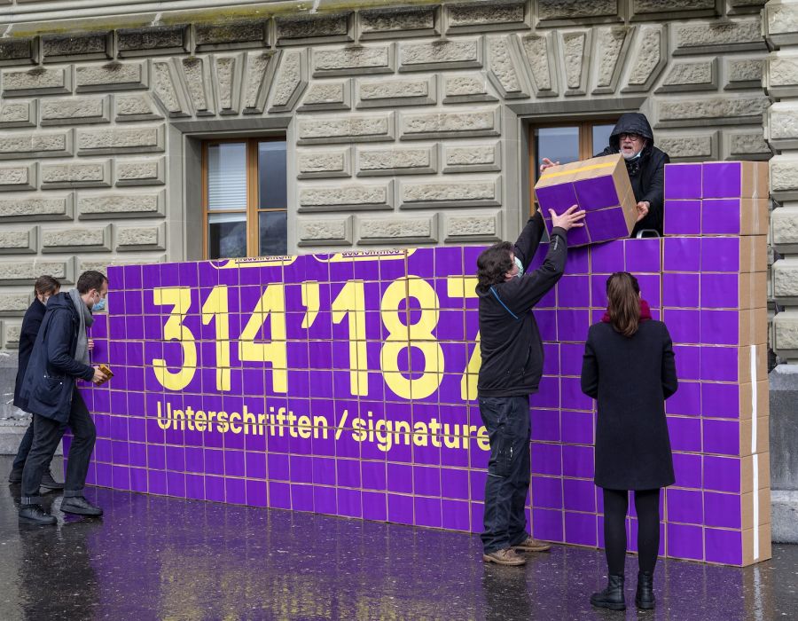 Montage d'un mur violet sur lequel on peut lire: "Pas touche aux rentes des femmes. 314187 signatures".