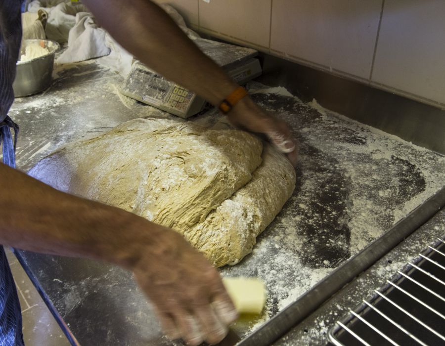 Les mains d'un boulanger pétrissent de la pâte.