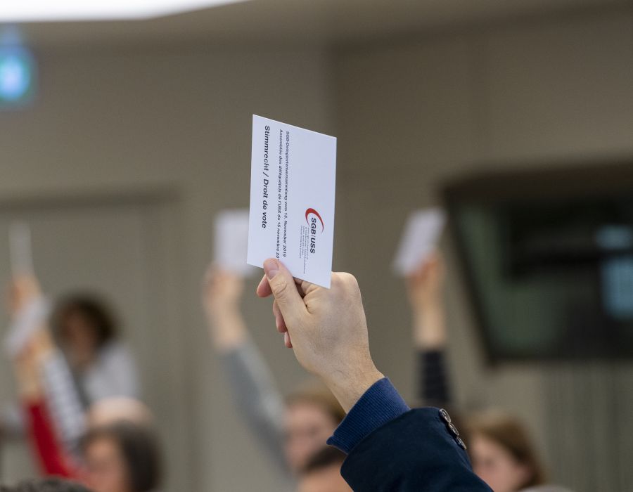 Une main tient une carte pour voter lors d'une assemblée.