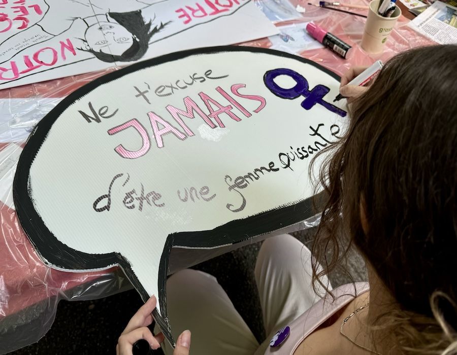 Une femme réalise une pancarte pour la grève féministe
