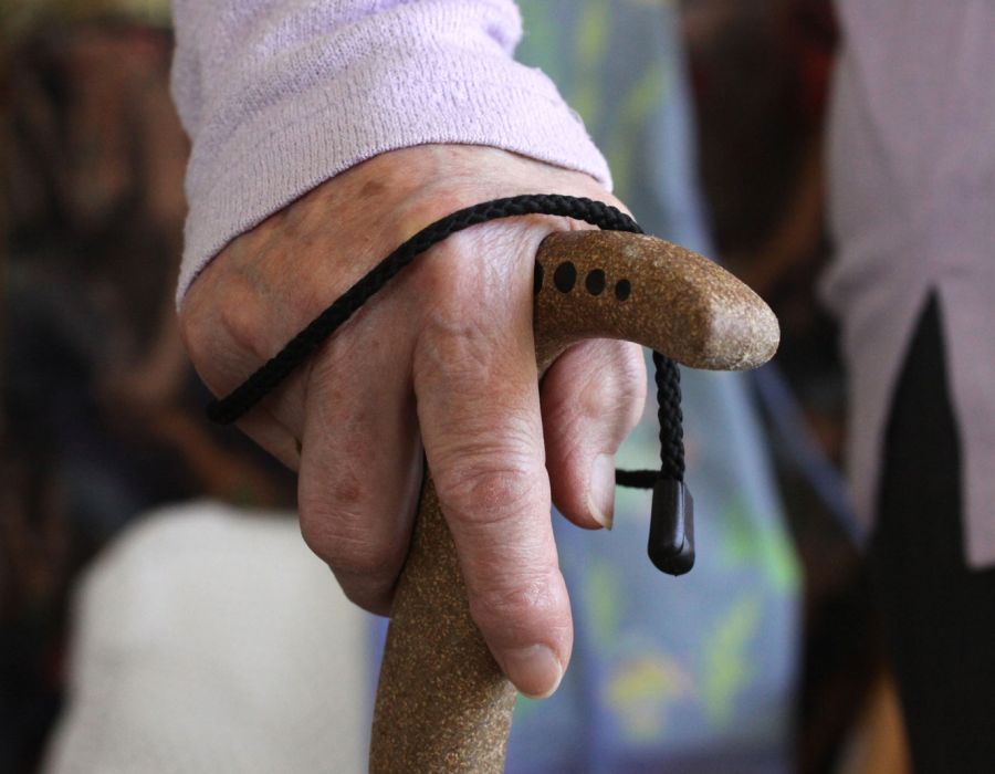 Gros plan sur la main d'une personne âgée appuyée sur une canne.