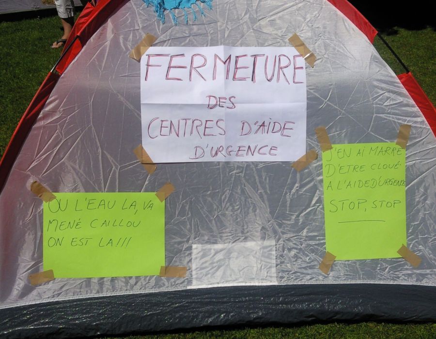 Une tente de camping avec un panneau: "Fermeture des centres d'aide d'urgence".