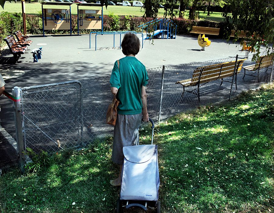 Photo d'une personne âgée devant une place de jeux.