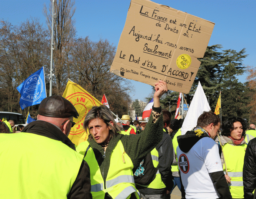Des gilets jaunes devant le Palais des nations à Genève avec une pancarte indiquant: La France est un Etat de droits où aujourd'hui nous avons seulement le droit d'être d'accord!