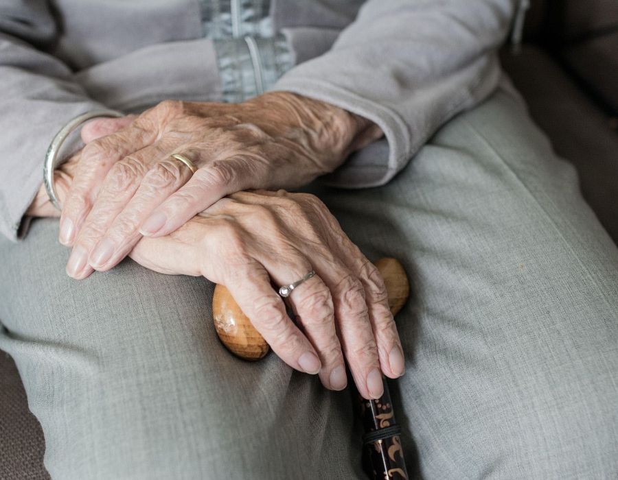 Mains croisées d'une vieille dame sur une canne.